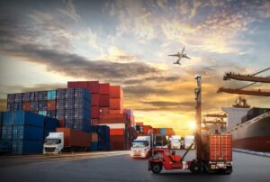 Containerlogistik mit Lkw, Schiff und Flugzeug bei Sonnenuntergang – symbolisch für internationale Lieferketten und steuerliche Herausforderungen für Unternehmen in Erlangen. Jetzt beraten lassen bei Ihrer Steuerkanzlei Gojowsky.